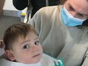 Baby with toilet seat stuck around his neck looking at the camera