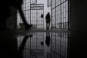 Persons enter the Sachsenhausen Nazi death camp through the gate with the phrase 'Arbeit macht frei' (work sets you free) in Oranienburg, about 30 kilometers (18 miles) north of Berlin, Germany, Tuesday, Jan. 25, 2022.