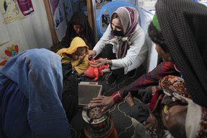 A nurse checks the weight of a child in the makeshift clinic organized by World Vision at a settlement near Herat, Afghanistan, on Dec. 16, 2021