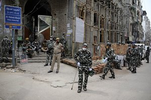 Indian paramilitary soldiers wearing face masks and gloves stand guard outside a mosque as police and local authorities clear the protest site of Shaheen Bagh as part of virus-containment measures, in New Delhi, India, Tuesday, March 24, 2020