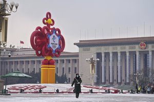 A paramilitary police officer wearing a face mask to protect from the coronavirus marches past a decoration for the Beijing Winter Olympics Games on display at Tiananmen Square in Beijing, Thursday, Jan. 20, 2022.