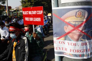 A poster with an X mark on an image of Commander-in-Chief Senior Gen. Min Aung Hlaing, also chairman of the State Administrative Council, is placed on a metal post as anti-coup protesters hold a rally in Mandalay, Myanmar, Saturday, Feb. 13, 2021