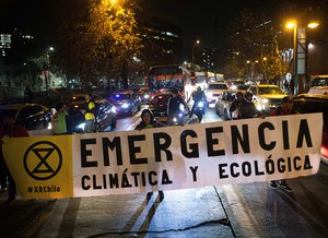 File - Members of the Extinction Rebellion, XR, environmentalist group block a street to demand global changes that reduce the effects of climate change, Friday, July 26, 2019 Local XR supporters are demanding that Chile declare a state of climatic emergency, reduce carbon dioxide emissions, and advance its decarbonization program by 2030.