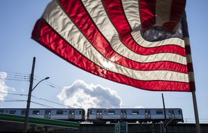 A Manhattan-bound D subway train rounds a curve as a U.S. flag flaps in the wind Thursday, April 9, 2020, in the Brooklyn borough of New York.