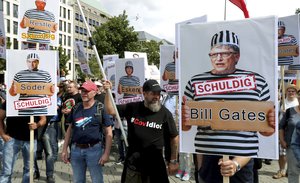 People attend a protest rally in Berlin, Germany, Saturday, Aug. 29, 2020 against new coronavirus restrictions in Germany, holding a sign with Bill Gates in prison clothes, reading "Guilty".