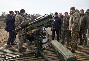 Ukrainian President Volodymyr Zelenskyy, center left, inspects anti-aircraft weapons during a military drill outside the city of Rivne, northern Ukraine, Wednesday, Feb. 16, 2022