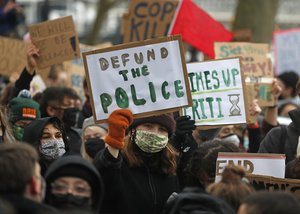 Demonstrators hold up placards as they gather outside New Scotland Yard in London, Sunday, March 14, 2021 during a protest over the abduction and murder of Sarah Everard and the subsequent handling by the police of a vigil honoring the victim.