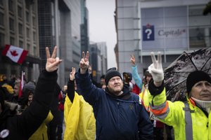 Protesters give peace signs in solidarity at a rally against COVID-19 restrictions outside Canada’s parliament building in Ottawa on Thursday, Feb. 17, 2022