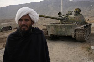 A Taliban fighter stands in front of an old destroyed Soviet tank used during the Soviet occupation, in Parwan province north of Kabul, Afghanistan, Saturday, Feb. 19, 2022.