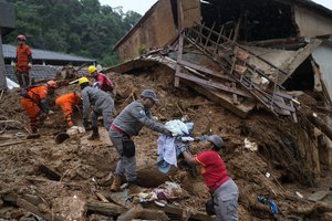 Rescue workers recover clothing from a home on the third day of efforts to find survivors and victims of deadly mudslides in Petropolis, Brazil, Friday, Feb. 18, 2022