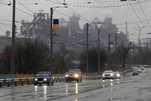 Cars drive past the Mariupol Metallurgical Plant in Mariupol, Ukraine, Thursday, Feb. 24, 2022