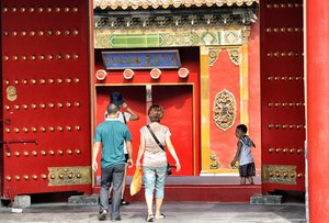 Three people walking toward red building, China