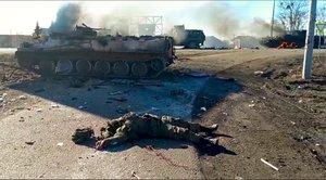 In this handout photo taken from video released by Ukrainian Police Department Press Service, a body of killed soldier lays on the ground next to wrecked military vehicles after an attack allegedly by separatists, or Russians in eastern Ukraine, Thursday, Feb. 24, 2022