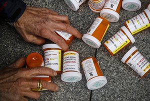 FILE - A protester gathers containers that look like OxyContin bottles at an anti-opioid demonstration in front of the U.S. Department of Health and Human Services headquarters in Washington, on April 5, 2019.