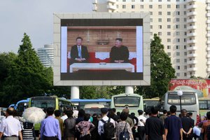 People watch a large screen showing an image of Chinese President Xi Jinping, left, meeting North Korean leader Kim Jong Un at Pyongyang Railway Station in Pyongyang, North Korea, Friday, June 21, 2019