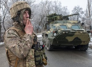 A Ukrainian soldier smokes a cigarette on his position at an armored vehicle outside Kharkiv, Ukraine, Saturday, Feb. 26, 2022. President Volodymyr Zelenskyy claimed Saturday that Ukraine's forces had repulsed the assault and vowed to keep fighting. "We will win," Zelenskyy said.