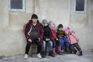 A pregnant woman and children sit on a bench in the improvised bomb shelter in a sports center, which can accommodate up to 2000 people, in Mariupol, Ukraine, Monday, Feb. 28, 2022.