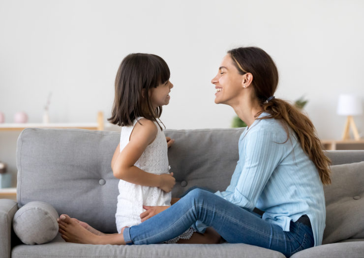 Photo of young girl and mom on the couch talking