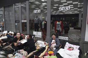 People sit on cots, at a reception center for displaced persons from Ukraine, at the Ukrainian-Polish border crossing in Korczowa, Poland, Saturday, March 5, 2022.