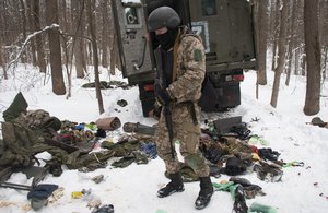 A volunteer of the Ukrainian Territorial Defense Forces inspects a damaged military vehicle in the outskirts Kharkiv, Ukraine's second-largest city, Monday, March 7, 2022.