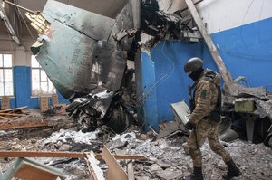 Ukrainian serviceman walks past the vertical tail fin of a Russian Su-34 bomber lying in a damaged building in Kharkiv, Ukraine, Tuesday, March 8, 2022.