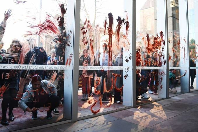 Protesters smear red ochre over the windows of the NSW Supreme Court