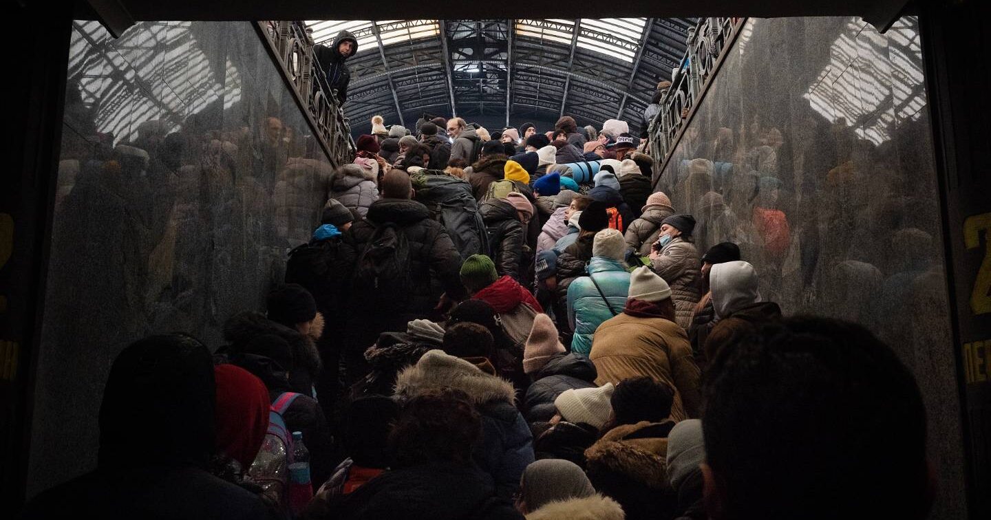 A crowd of people in winter coats climbs a staircase