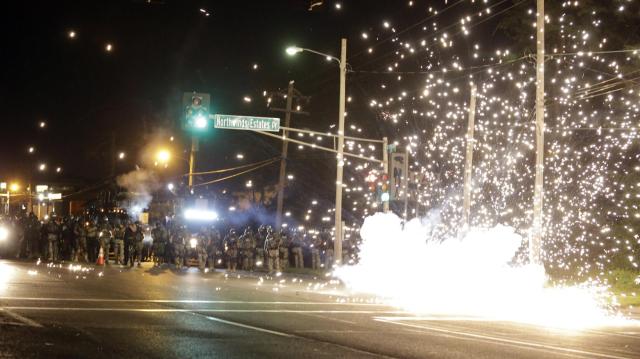 Armed riot cops set off an incendiary device in Ferguson, MO Credit: AP Images