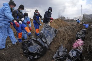 Dead bodies are placed into a mass grave on the outskirts of Mariupol, Ukraine, Wednesday, March 9, 2022, as people cannot bury their dead because of the heavy shelling by Russian forces.