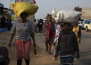 Women carry sacks on their heads down a busy street in the Diepsloot Township, north of Johannesburg, Thursday, Aug. 26, 2021.