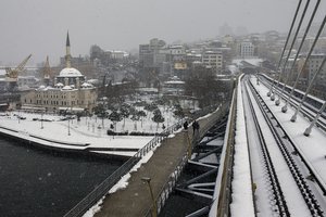 Pedestrian walk next to Golden Horn metro station during a snow fall in Istanbul, Turkey, Friday, March 11, 2022