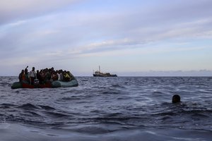 A migrant who was aboard a precarious rubber boat with others jumps to the water as they are rescued by a team of the Sea Watch-3, around 35 miles away from Libya, in Libyan SAR zone, Monday, Oct. 18, 2021