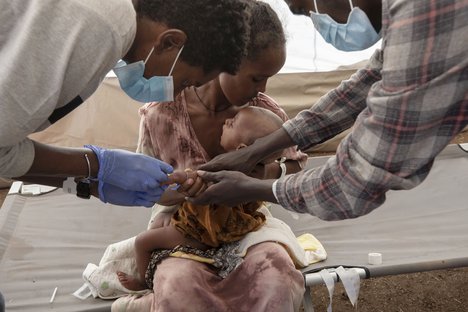 File - A Tigray woman who fled the conflict in Ethiopia's Tigray region, holds her malnourished and severely dehydrated baby as nurses give him IV fluids, at the Medecins Sans Frontieres (MSF) clinic, at Umm Rakouba refugee camp in Qadarif, eastern Sudan, Saturday, Dec. 5, 2020.