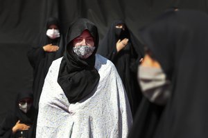 Women wearing protective face masks to help prevent spread of the coronavirus mourn during an annual ceremony commemorating Ashoura, the anniversary of the 7th century death of Imam Hussein, a grandson of Prophet Muhammad, and one of Shiite Islam's most beloved saints, who was killed in a battle in Karbala in present-day Iraq, at the Saleh shrine in northern Tehran, Iran, Sunday, Aug. 30, 2020.