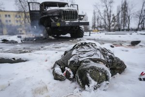 The body of a serviceman is coated in snow next to a destroyed Russian military multiple rocket launcher vehicle on the outskirts of Kharkiv, Ukraine, Friday, Feb. 25, 2022