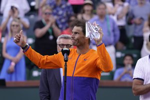 Rafael Nadal, of Spain, holds up his second place trophy with bandaged fingers, after losing to Taylor Fritz