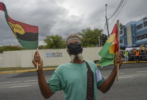 A man protests outside the British Council to demand an apology and slavery reparations during a visit to the former British colony by the Duke and Duchess of Cambridge, Prince William and Kate, in Kingston, Jamaica, Tuesday, March 22, 2022