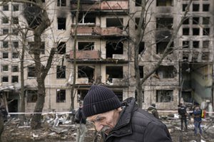 File - An elderly man walks outside an apartment block which was destroyed by an artillery strike in Kyiv, Ukraine, March 14, 2022.