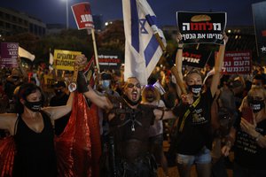 Protesters hold signs during a demonstration against Israel's government in Rabin square in Tel Aviv, Israel, Saturday, July 11, 2020.