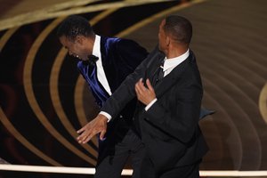 Will Smith, right, hits presenter Chris Rock on stage while presenting the award for best documentary feature at the Oscars on Sunday, March 27, 2022, at the Dolby Theatre in Los Angeles.