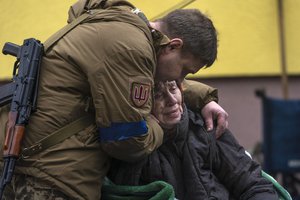 A soldier comforts Larysa Kolesnyk, 82, after she was evacuated from Irpin, on the outskirts of Kyiv, Ukraine, Wednesday, March 30, 2022