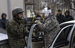 A wounded man talks to a soldier, left, after being evacuated from Irpin, on the outskirts of Kyiv, Ukraine, Wednesday, March 30, 2022