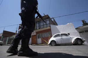 A police officer stands guard outside the red brick house where journalist Armando Linares was shot dead, in Zitacuaro, Michoacan state, Mexico, Wednesday, March 16, 2022