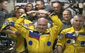 In this photograph taken from a video provided by the Roscosmos Space Agency, Russian cosmonauts Оleg Аrtemiev, center, Denis Мatveev, right, and Sergei Korsakov, left, wear their yellow uniforms with blue details upon arrival at the International Space Station, Friday, March 18, 2022.