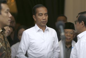 Incumbent Indonesian President Joko Widodo, center, walks with running mate Ma'ruf Amin, second from right, after a meeting with leaders of their coalition parties in Jakarta, Indonesia, Thursday, April 18, 2019