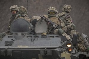 Ukrainian servicemen sit atop armored personnel carriers driving on a road in the Donetsk region, eastern Ukraine, Thursday, Feb. 24, 2022