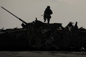 A Ukrainian serviceman walks on a destroyed Russian fighting vehicle in Bucha, Ukraine, Thursday, April 7, 2022.