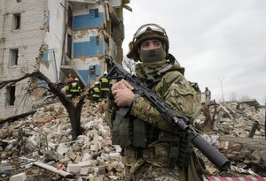 A Ukrainian soldier stands near an apartment ruined from Russian shelling in Borodyanka, Ukraine, Wednesday, Apr. 6, 2022