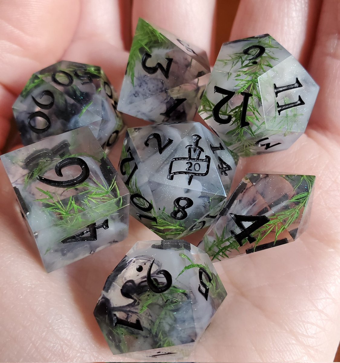 A set of dice with green leaves, white and black swirls, and black painted numbers.