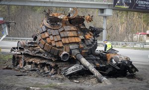 A road worker examines a damaged Russian tank on a highway to Kyiv, Ukraine, Monday, Apr. 11, 2022.